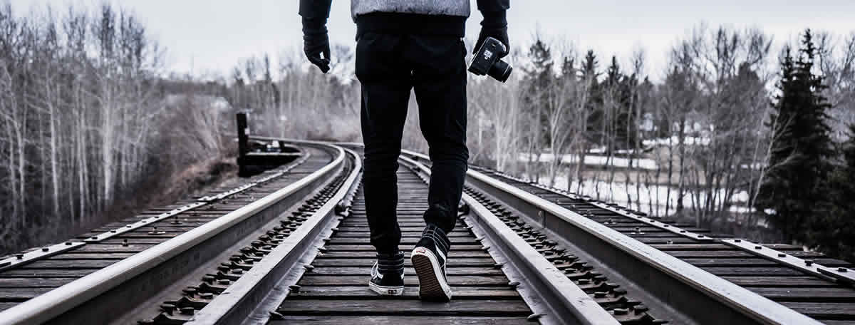 A man walking down railroad tracks into the distance.